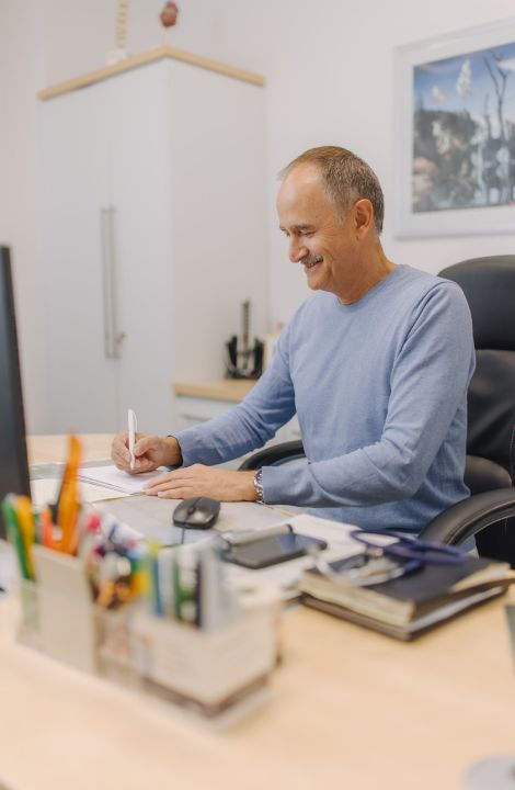 Hausarzt Dr. Doßow arbeitet konzentriert an Patientenunterlagen in seiner Praxis in Magdeburg.
