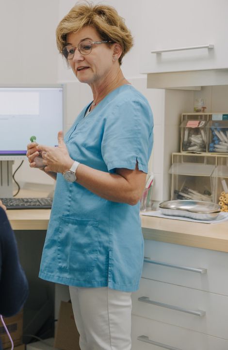 Medizinische Fachangestellte erklärt einer Patientin die Anwendung eines Diagnosegeräts in der Praxis.